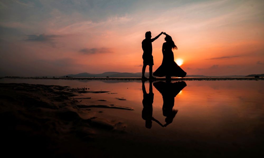 "Silhouette of a couple dancing on the beach at sunset, symbolizing the journey of love from dating to marriage