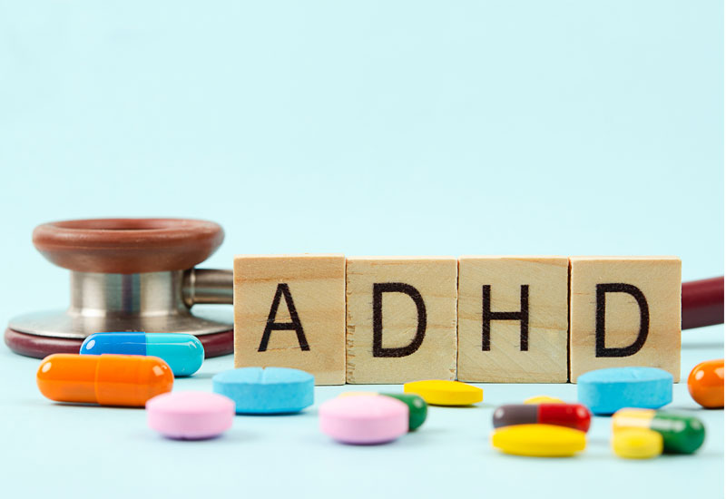 Wooden tiles spelling adhd with pills showing the multitude of adhd meddication options for adolescents